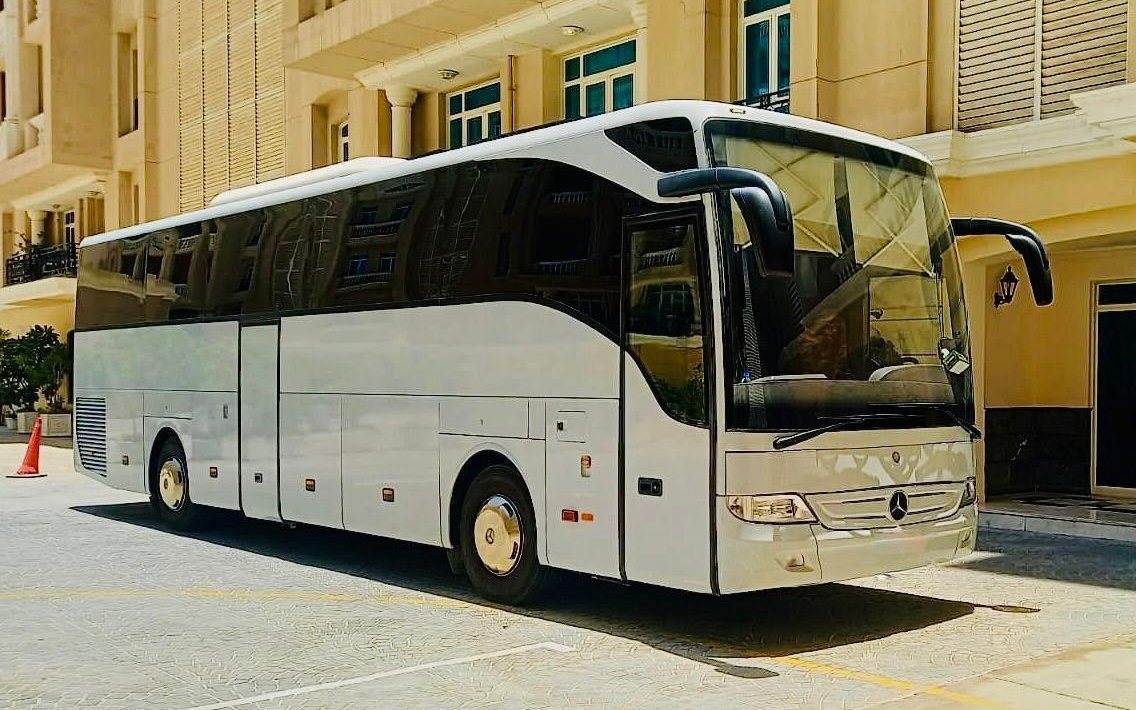 Dunescape's white Mercedes-Benz Tourismo coach waiting outside a Doha hotel