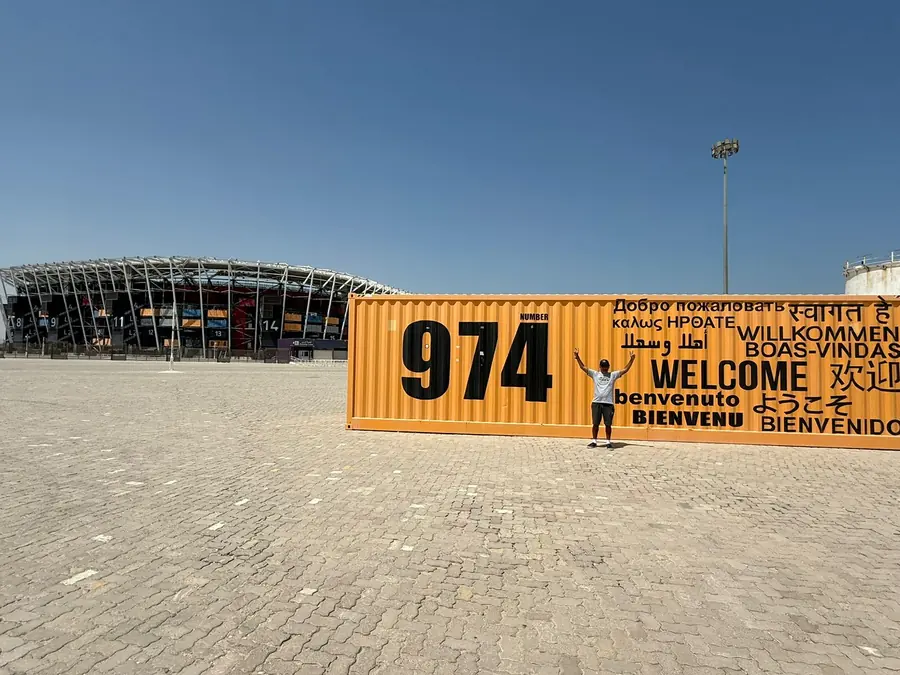 A guest beside the 974 container with the stadium behind