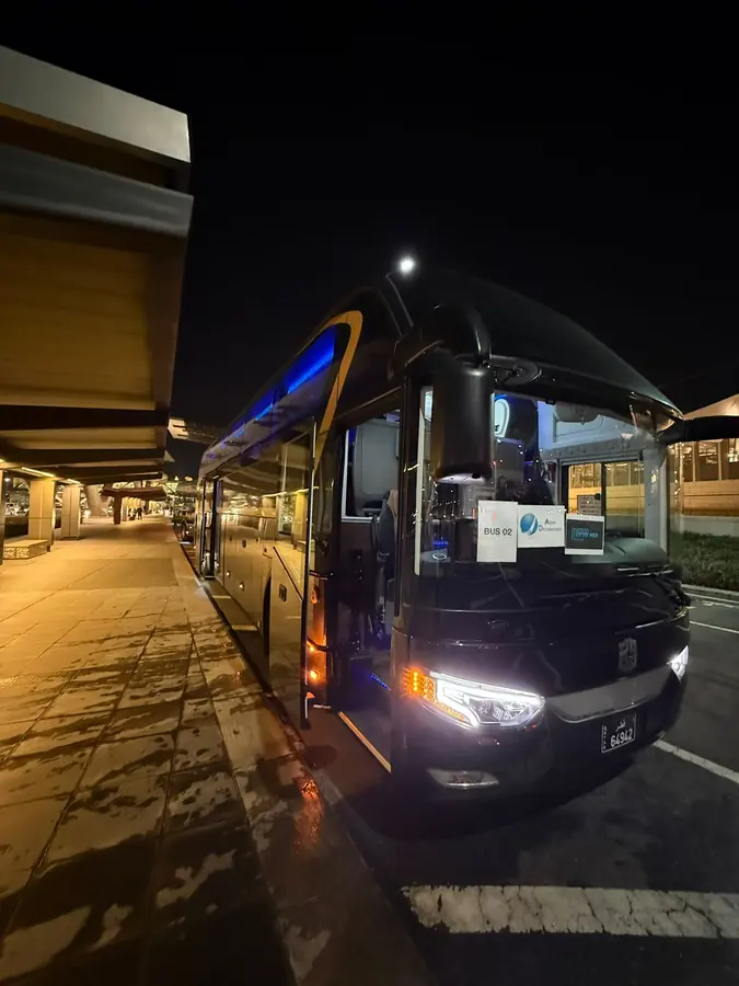 A black touring coach waiting at the kerb in Doha after dark