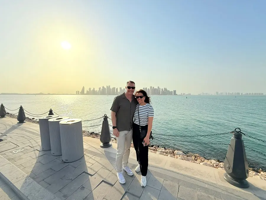A couple on the Corniche with the West Bay skyline behind them at sunset