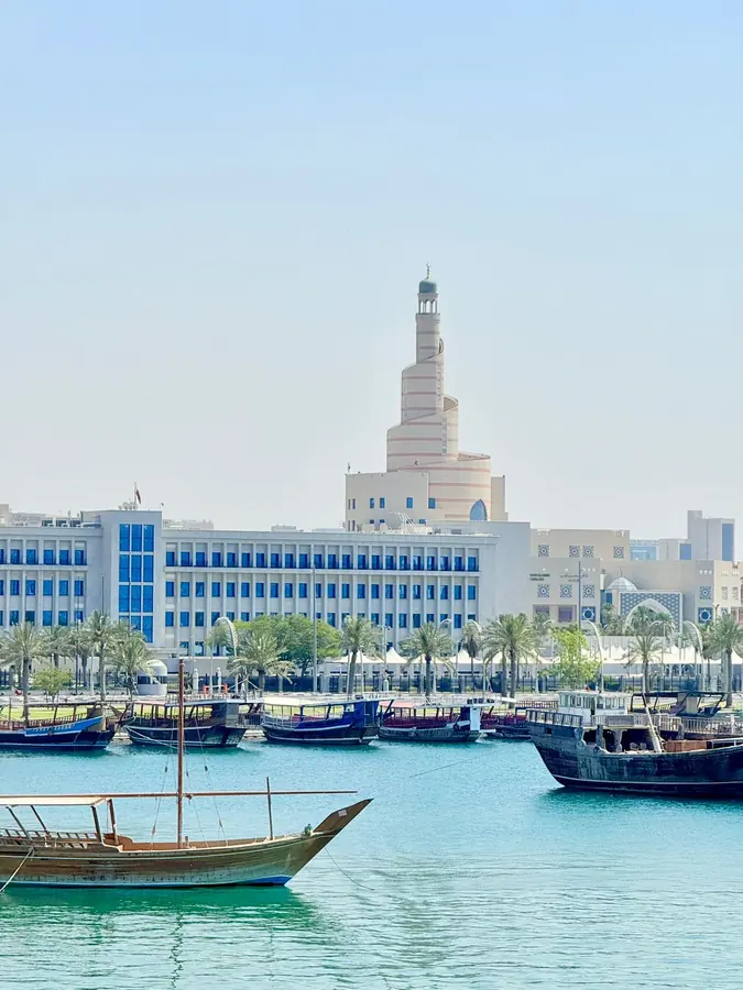 Wooden dhows moored below the spiral minaret of the Fanar centre