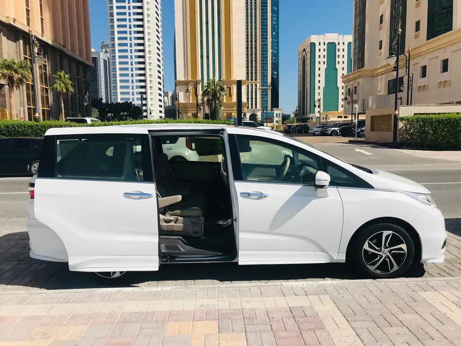 A white Honda Odyssey with the sliding door open for boarding