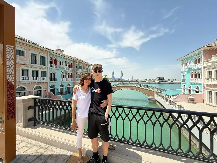 Two guests on a bridge among the pastel facades of Qanat Quartier