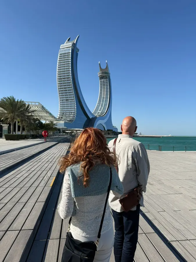Two guests walking the boardwalk toward the Katara Towers
